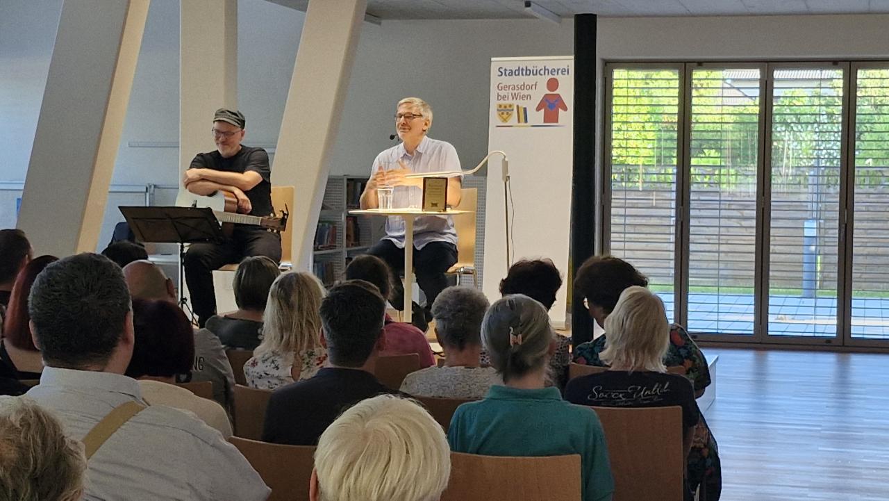 auf der Bühne die beiden Künstler, links Helmuth Martin Wolf mit Gitarre und rechts der Autor Stefan Franke