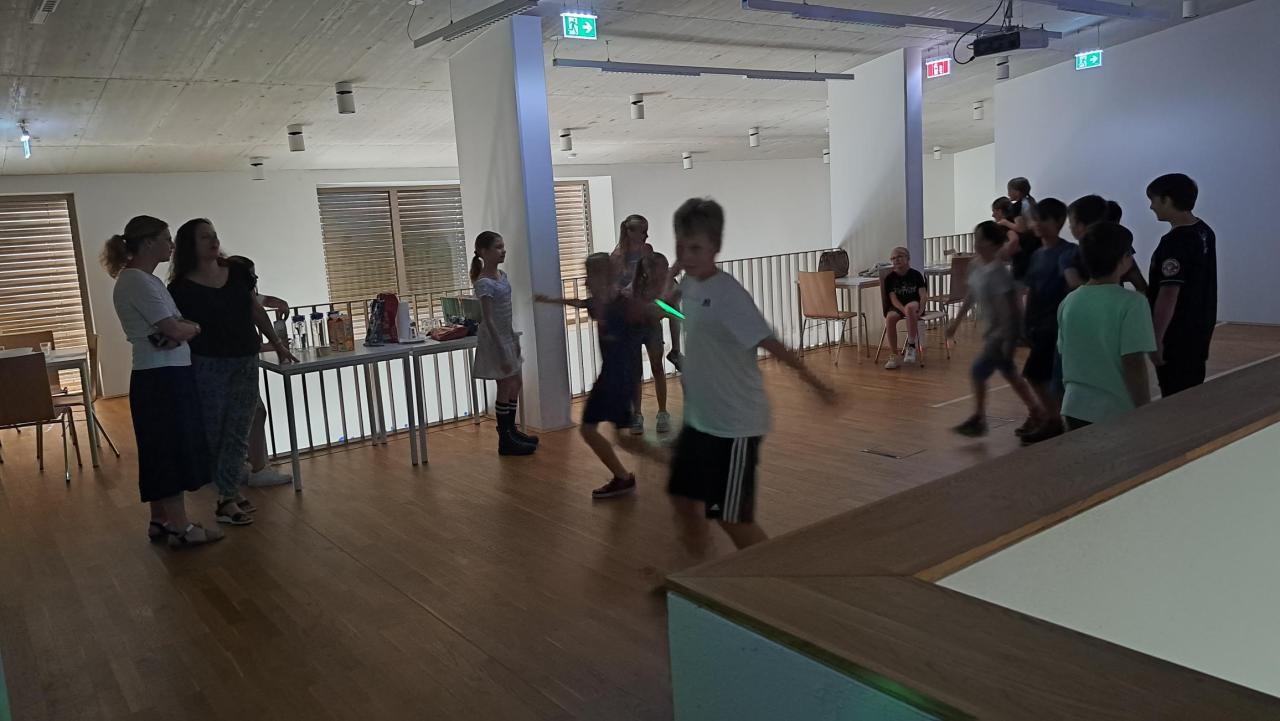 Volksschuldirektiorin und Klassenlehrerin schauen den tanzenden Kindern zu