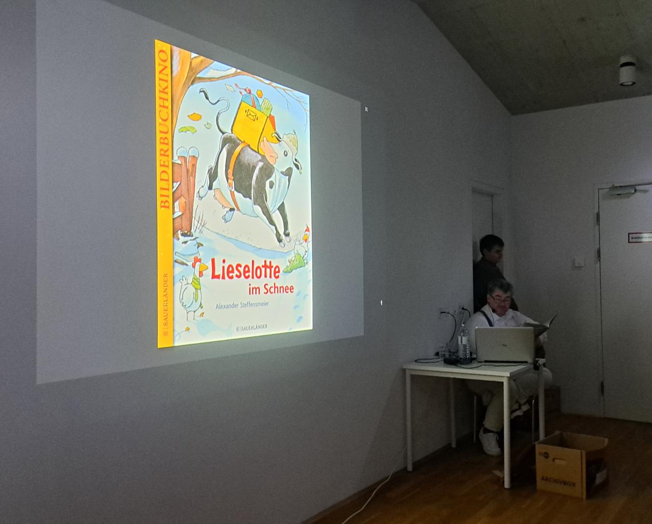 ein Bild an die Wand projiziert und ein Mann, der eine Geschichte vorliest