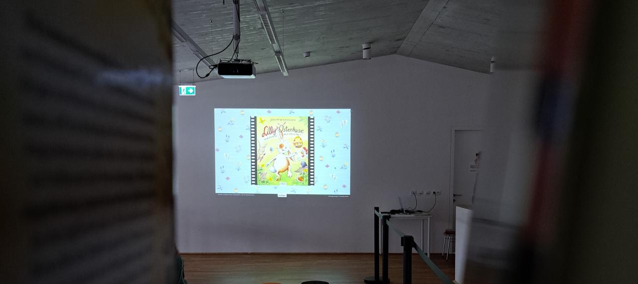 Blick nach vorne auf die Leinwand, auf der das Buchcover zu sehen ist