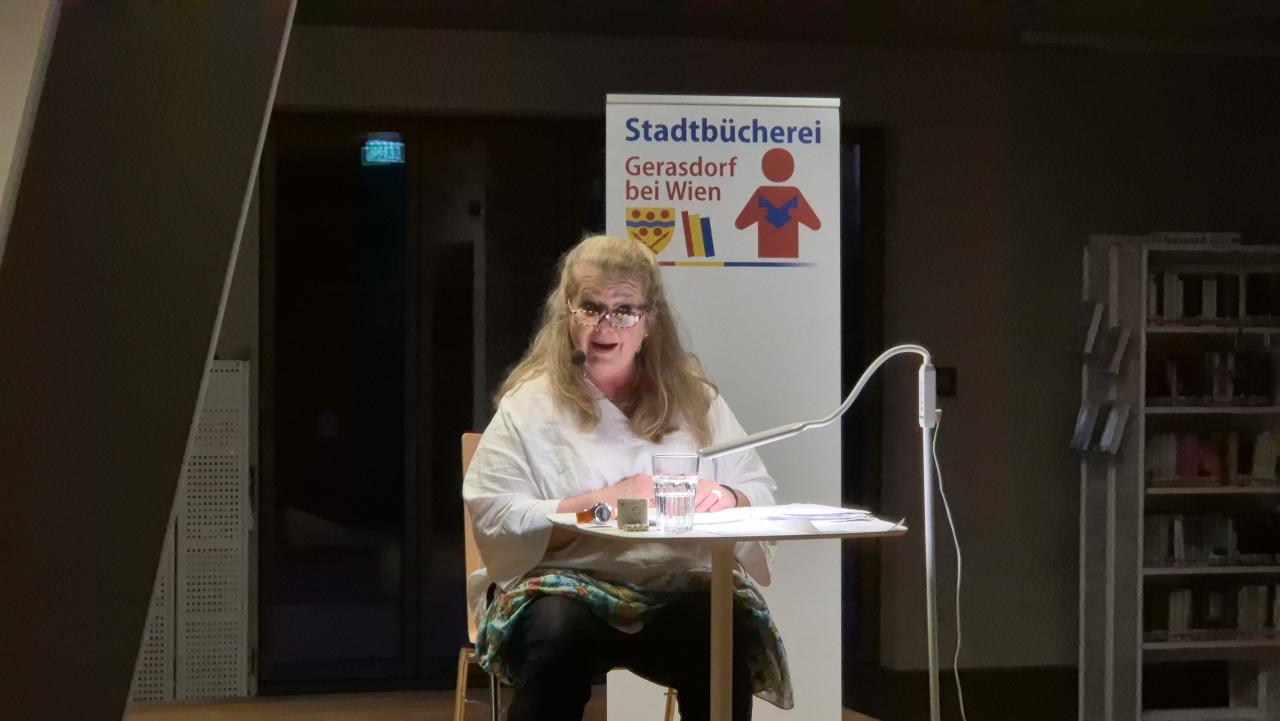eine Frau sitzt auf der Bühne und erzählt