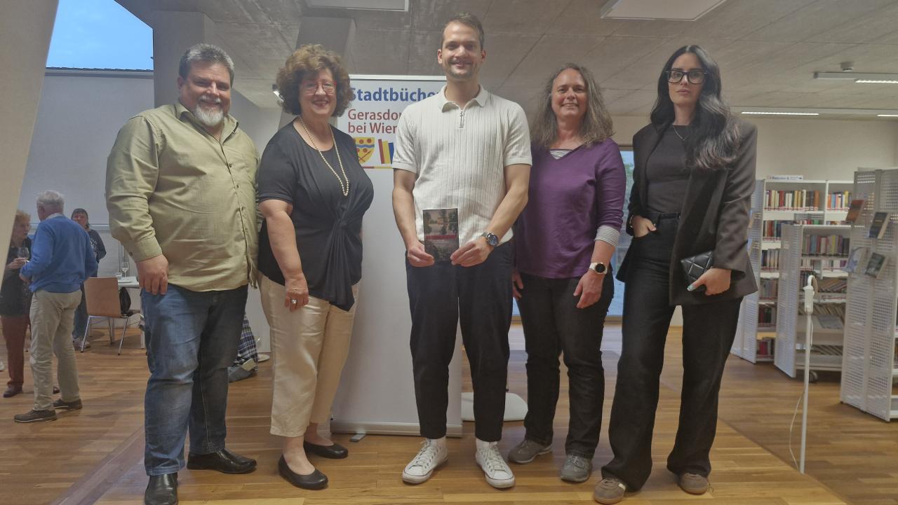 Gruppenbild, man sieht 5 Personen auf der Bühne, im Hintergrund das Banner der Bücherei