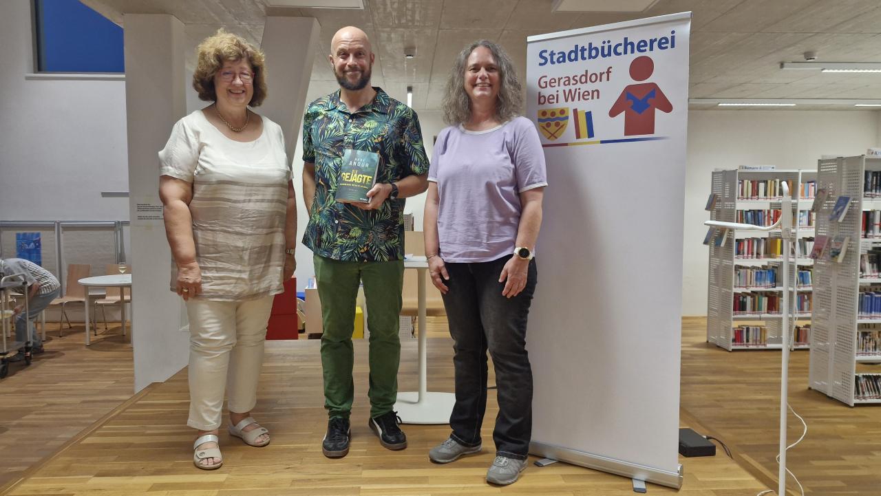 Gruppenbild, 3 Menschen stehen auf der Bühne, 2 Frauen und 1 Mann