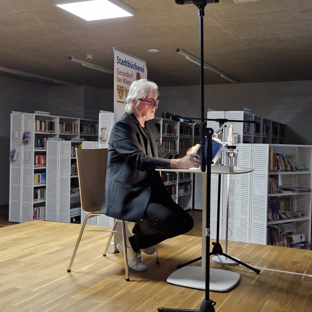 Mann mit Buch auf der Bühne, sitzend