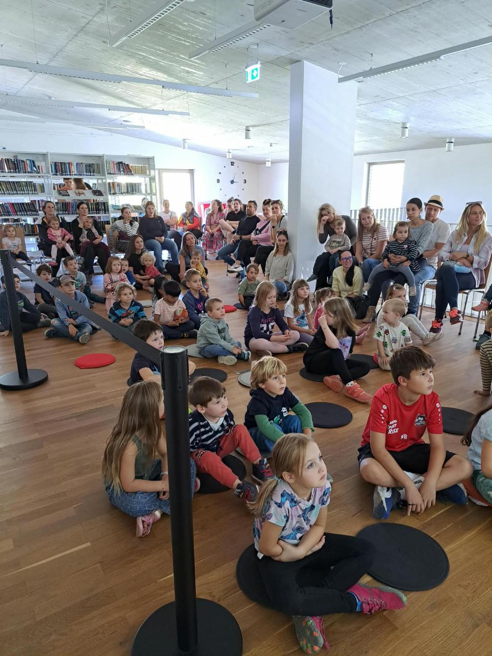 sitzende Kinder am Boden und Erwachsene auf Sesseln